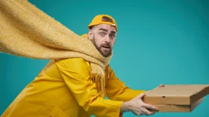 Entregador com expressão divertida representando o conceito de frases engraçadas para delivery, usando uniforme amarelo enquanto entrega uma caixa de pizza. A imagem ilustra como o humor no delivery pode transformar a experiência do cliente através de mensagens engraçadas e criativas na entrega